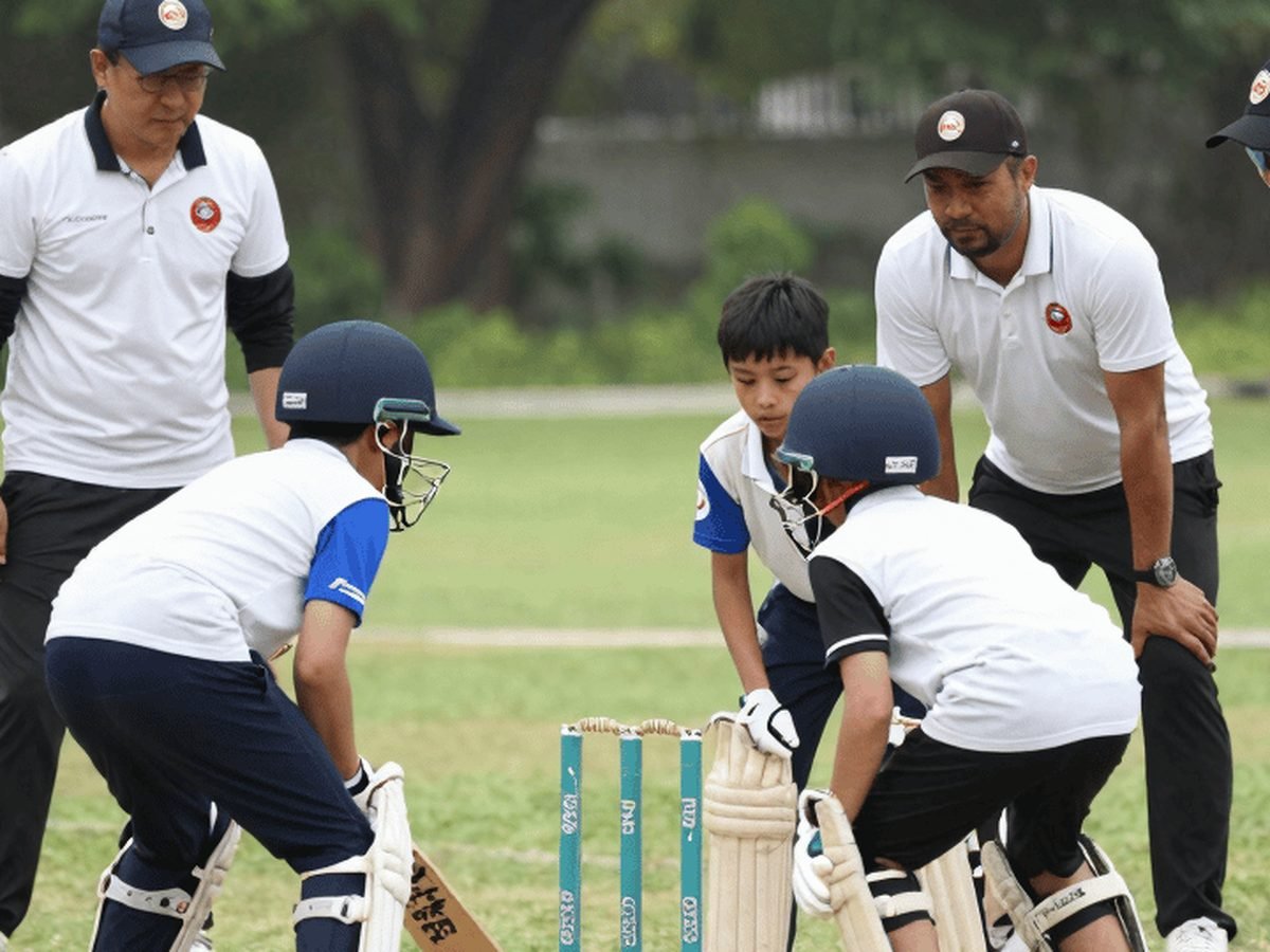 Young players gathered around the stumps during a coaching session.